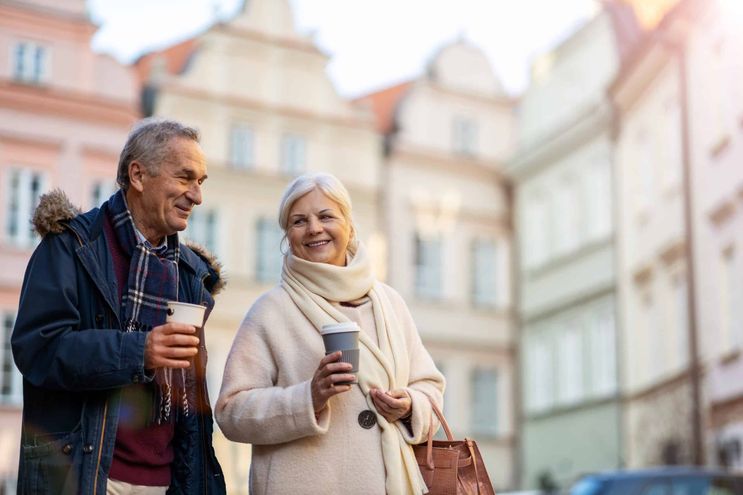 para seniorów spacerująca z kawą po starówce